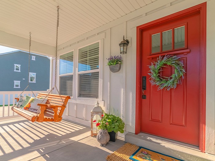 Front porch of a house with a red wood door.